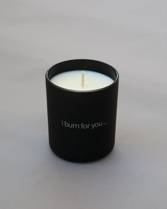 Black candle holder with a white candle labeled 'i burn for you' on a light gray background